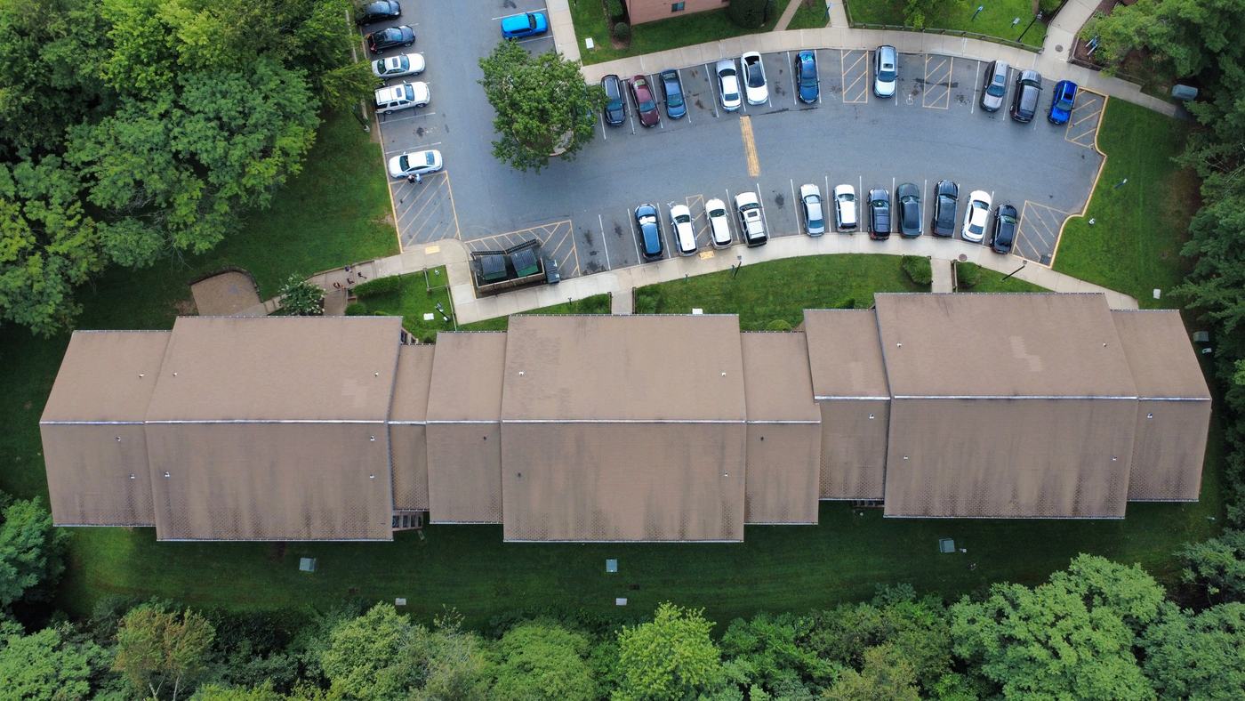 Aerial photograph of a single long apartment building, showing the connected multi-wing roofline and the facets that were measured.