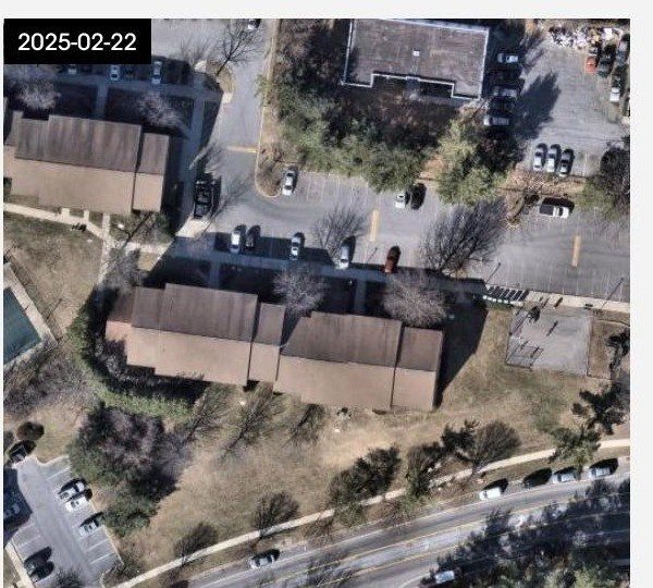 Timestamped satellite image dated February 2025 showing the same apartment building and roof, visibly unchanged from the 2016 image.